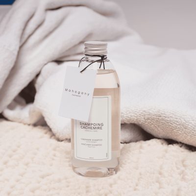 Shampoing spécial cachemire posé sur un plaid, produit recommandé pour laver le cachemire.