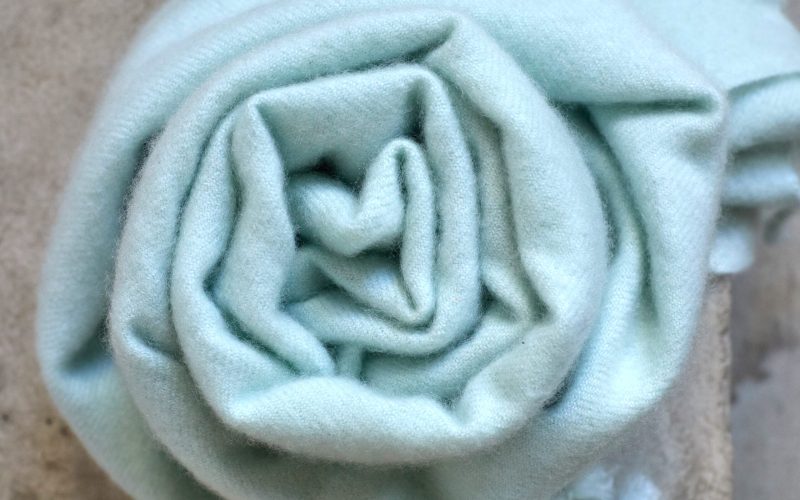 Cachemire bleu pâle roulé, texture douce nécessitant un lavage délicat.